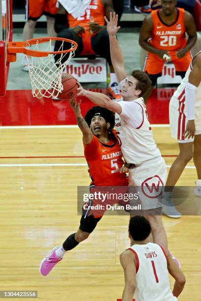 Andre Curbelo of the Illinois Fighting Illini attempts a layup while being guarded by Jonathan Davis and Nate Reuvers of the Wisconsin Badgers in the...