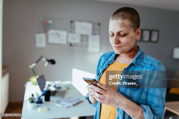 bald woman in office using smart phone - cellphone cancer illness stock pictures, royalty-free photos & images