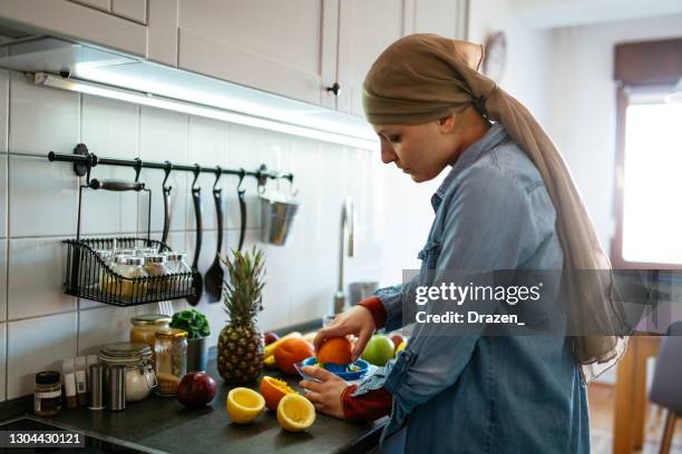 woman with headscarf suffering from cancer making lemonade in kitchen - survival food stock pictures, royalty-free photos & images