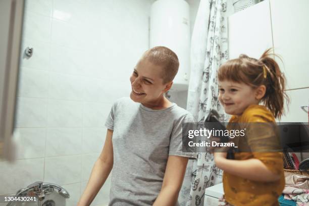 cancer patient woman in bathroom shaving or trimming her hair with her daughter - shaving head stock pictures, royalty-free photos & images