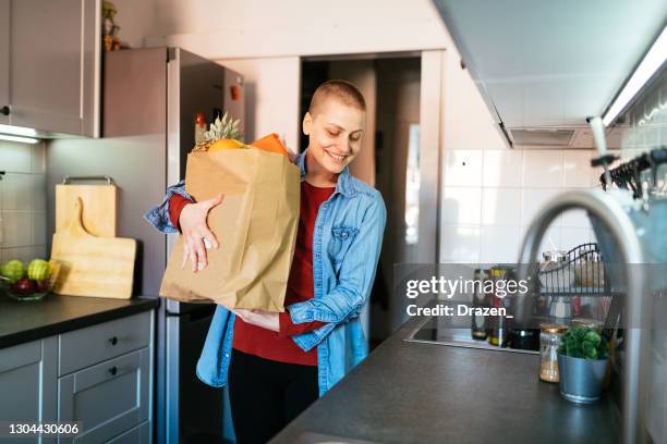 mulher com câncer volta para casa com saco de compras com mantimentos - chemotherapy drug - fotografias e filmes do acervo