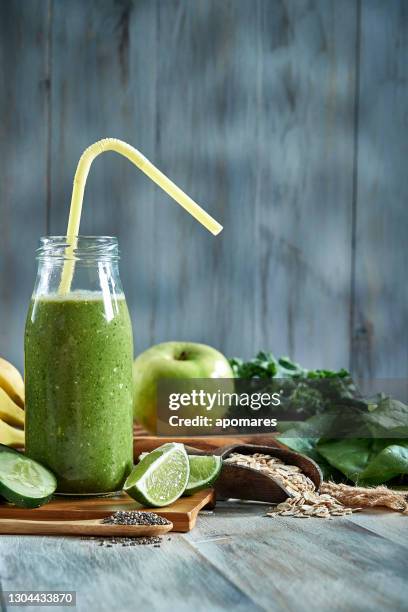 healthy food: green detox smoothie in bottle on a rustic table. - detox drink stock pictures, royalty-free photos & images