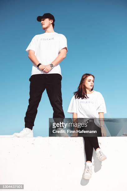 young couple together on concrete wall fashion portrait. - shirt stock pictures, royalty-free photos & images