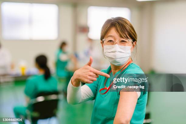 portrait of happy frontline helathcare worker showing her arm and smiling for camera after getting vaccinated - vaccine confidence stock pictures, royalty-free photos & images