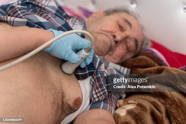 verpleegster - medisch technicus voert thuis echografisch hartonderzoek en diagnose uit voor de oudere 97-jarige mannelijke patiënt, met behulp van een draagbaar echoapparaat. - 50 54 years stockfoto's en -beelden
