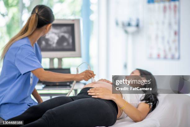 pregnant woman receiving ultrasound - ultrasound scan stock pictures, royalty-free photos & images