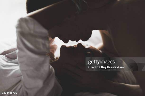 close-up silhouette of couple kissing with love and passion in bed - couple cuddling in bed stock pictures, royalty-free photos & images