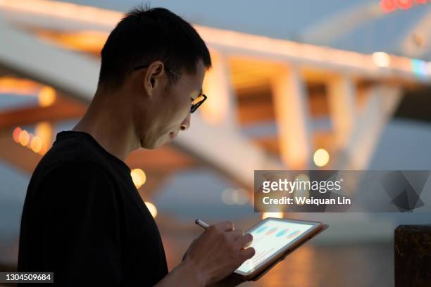 asian man using tablet at night - big data stockfoto's en -beelden