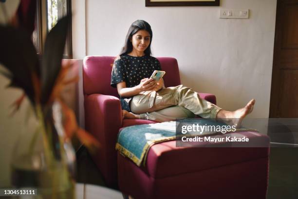 woman sitting on a sofa couch and using phone - daily life in india bildbanksfoton och bilder