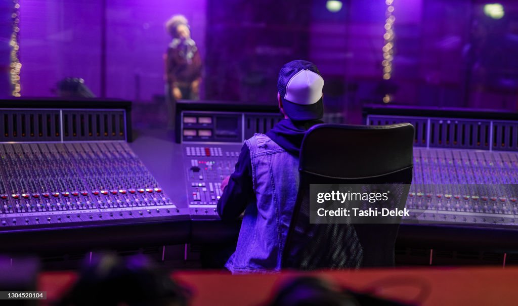 Female Vocalist And Sound Engineer Working In Studio
