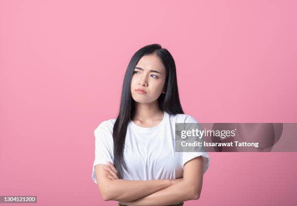 young asian woman get bored, upset, look at copy space, isolated on pink background. pretty girl gesturing on face like a bad mood, unhappy, touchy, bored something. she look upward, feel annoyed - annoyed face brunnette stock pictures, royalty-free photos & images