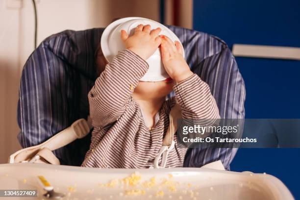 toddler eating with the face in the plate - baby eating stock-fotos und bilder