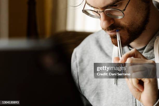 pensive man with pen working at home - iq test fotografías e imágenes de stock