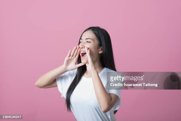 young asian woman shouting on pink background - shout photos et images de collection
