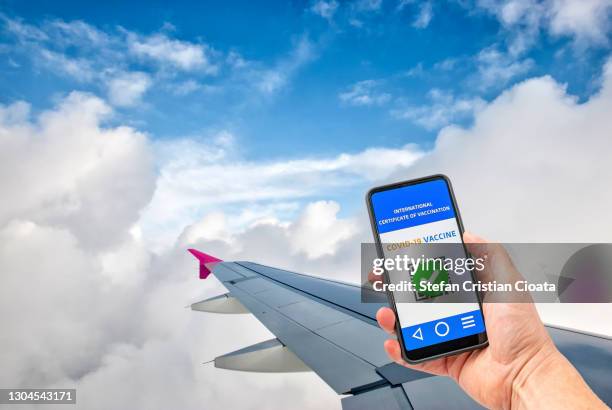 human hand holding mobile device with digital vaccination passport - impfpass reisedokument stock-fotos und bilder