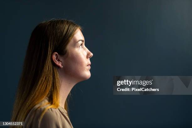 porträt junge geschäftsfrau mit blick auf das licht - dunkler hintergrund frau quer stock-fotos und bilder