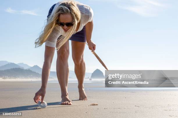 woman collects seashells on empty beach - costa de oregon imagens e fotografias de stock