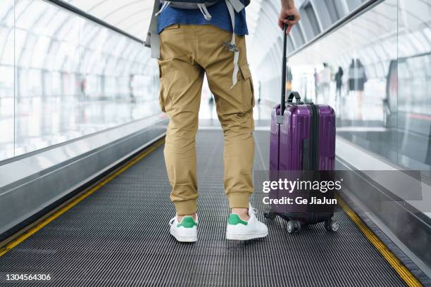 a traveler walking on moving walkway in the airport - baggage claim imagens e fotografias de stock