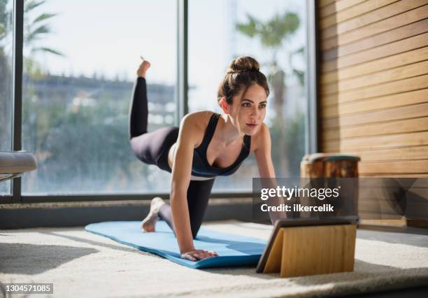 retrato de una hermosa mujer entrenando en casa y viendo lecciones en línea en la tableta digital - actividades y técnicas de relajación fotografías e imágenes de stock