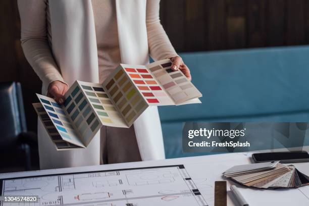 de juiste kleur kiezen: anonieme vrouwelijke architect die aan een project in haar kantoor werkt - color image stockfoto's en -beelden