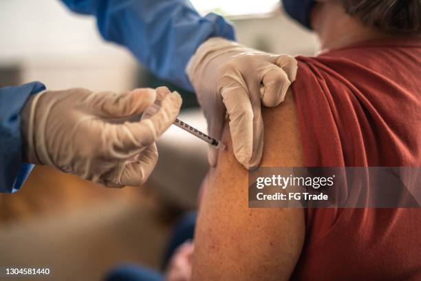 vaccine being applied on senior woman's arm - epidemiology stock pictures, royalty-free photos & images