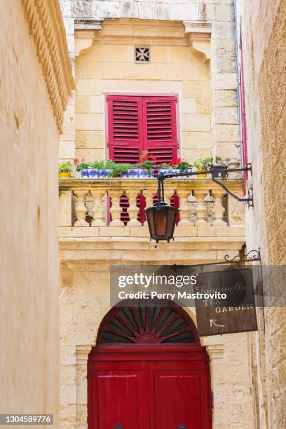 old architectural building facade and balcony decorated with red pelargonium - geranium flowers - mdina stock pictures, royalty-free photos & images
