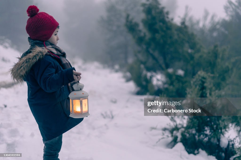 Boy with lantern in the snow