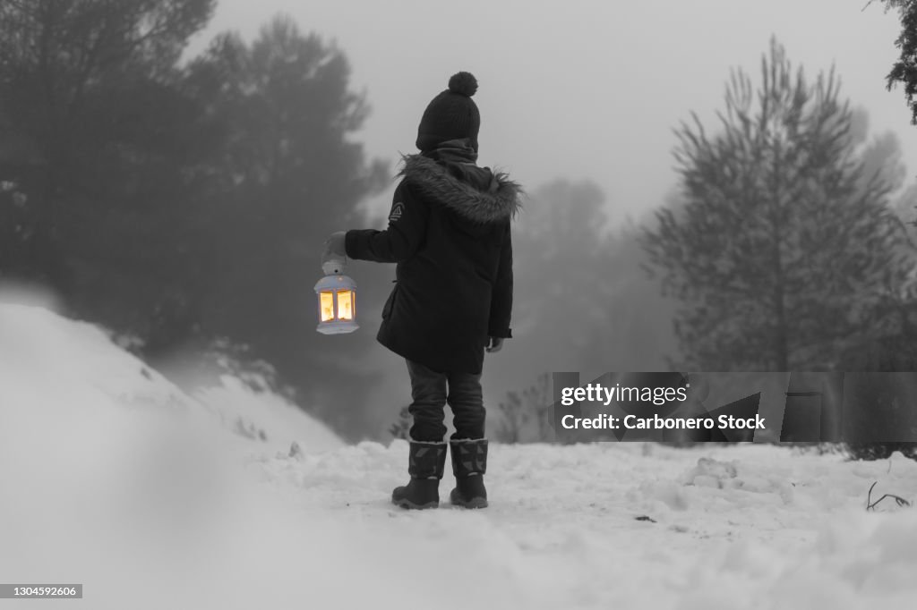 Boy with lantern in the snow