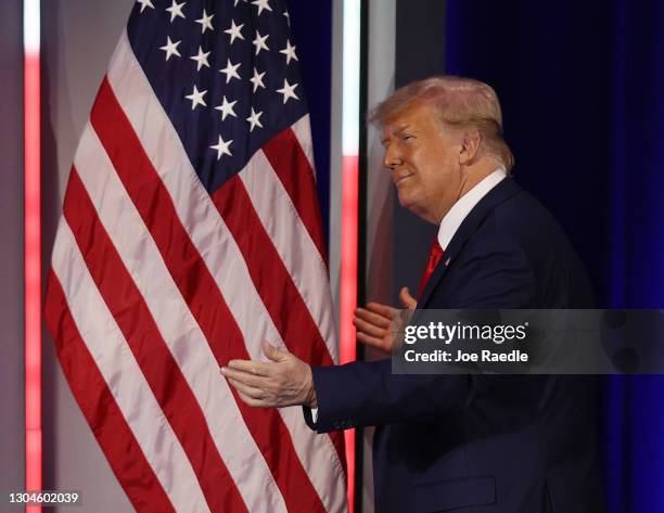 Former President Donald Trump embraces the American flag as he arrives on stage to address the Conservative Political Action Conference held in the...