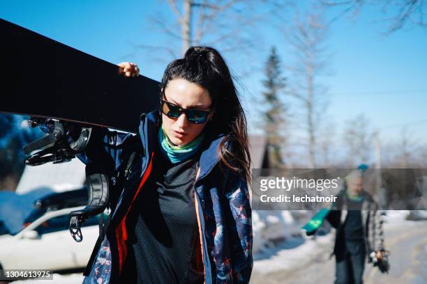 man and woman carrying equipment to the ski slope - snow board stock pictures, royalty-free photos & images