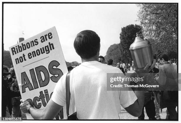 Activist holding a poster that reads RIBBONS ARE NOT ENOUGH and a funeral urn with human ash during a demonstration in November 1992 in Washington,...