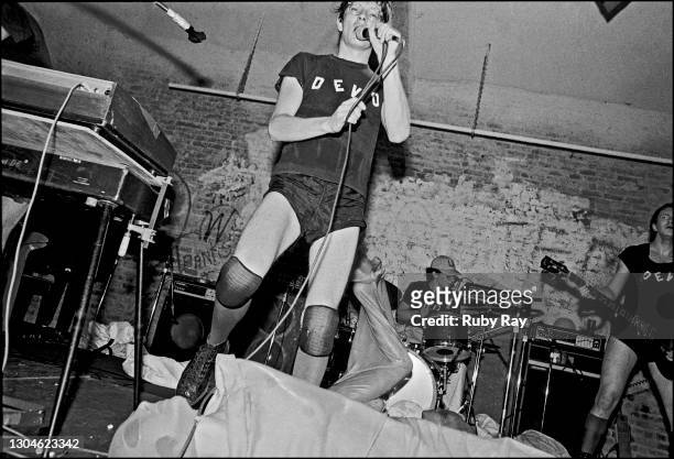 An unidentified woman, wrapped in plastic and nylons, rolls on the stage as American New Wave band Devo perform at the Mabuhay Gardens, San...
