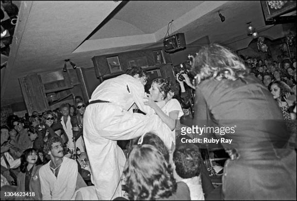 American New Wave musician Mark Mothersbaugh, of the group Devo, jumps into the audience and grab the hair of an audience member, 1977. The act had...