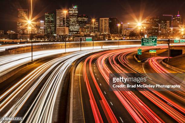 denver cityscape with light trails from i-25 in the foreground - denver street stock pictures, royalty-free photos & images