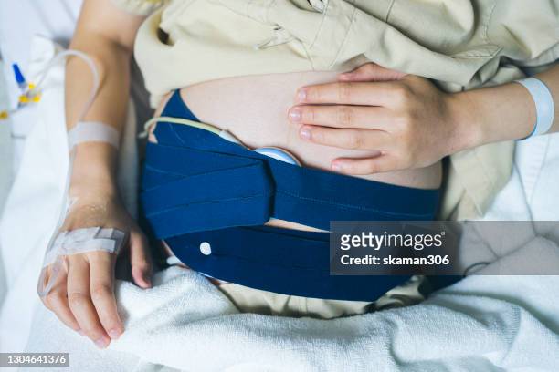 asian female pregnant and wearing maternity wears and using fetal monitoring checking pulse baby inside - 心臓刺激伝導系 ストックフォトと画像