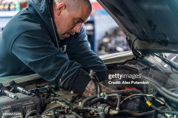 Repairman Auto Mechanic Caucasian White Man With Tattoos On Hands Working  In A Car Repair Shop Fixing The Electrical Wires Nearby The Engine Under  The Hood High-Res Stock Photo - Getty Images