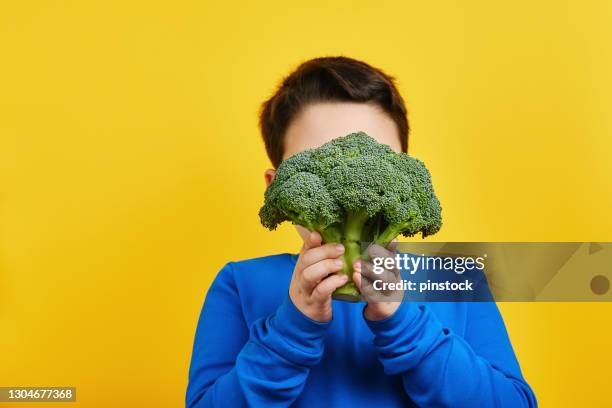 child holding vegetable on yellow background - broccoli white background stock pictures, royalty-free photos & images