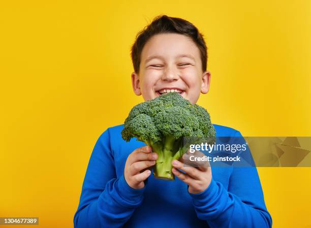 child holding vegetable on yellow background - broccoli white background stock pictures, royalty-free photos & images