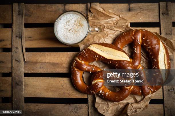 deutsche brotbrezeln mit bier auf einer holztischplatte - breze stock-fotos und bilder