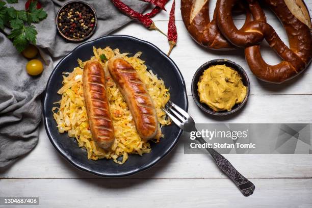 bayerische würstchen mit sauerkraut auf dem teller - choucroute stock-fotos und bilder