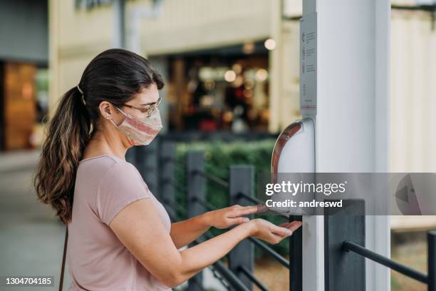 mulher limpando mãos / compras durante a pandemia coronavírus - hand sanitiser - fotografias e filmes do acervo
