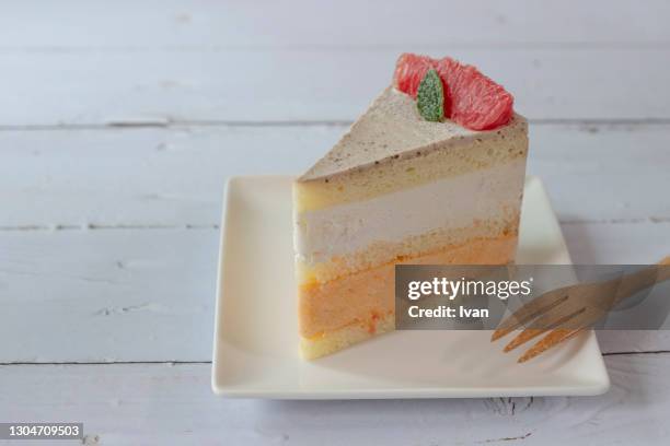 creamy sliced fruit grapefruit cake on white plate - gateaux stockfoto's en -beelden
