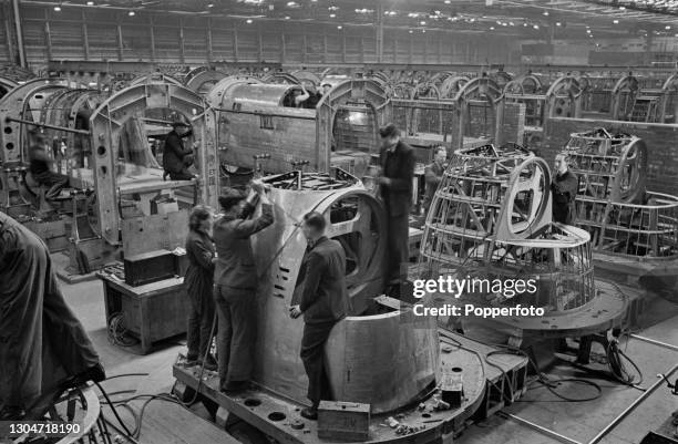 Four aircraft workers work on the fabrication of nose sections of Avro Lancaster heavy bombers under construction on a production line at an Avro...