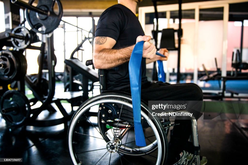Middle-aged man in a wheelchair exercising in the gym stock photo