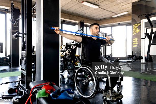 middle-aged man in a wheelchair exercising in the gym stock photo - spinal cord injury stock pictures, royalty-free photos & images