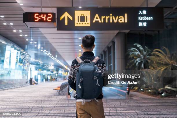 a traveler walking on moving walkway in the airport - singapore airport stock pictures, royalty-free photos & images