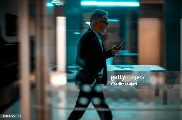 zakenman die op telefoon terwijl het lopen spreekt - smart numbers office stockfoto's en -beelden