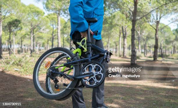 woman preparing her folding bicycle outdoors in forest. - foldable stock pictures, royalty-free photos & images