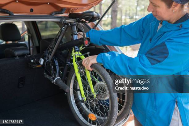 women taking his bicycle out from the trunk of a car. - foldable stock pictures, royalty-free photos & images