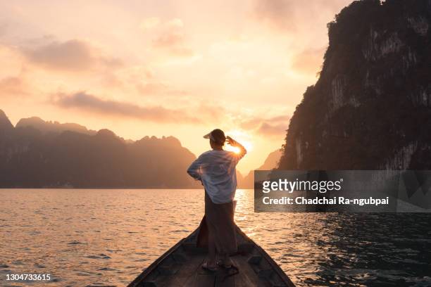 happy young woman tourist in asian hat on the boat at lake - south asian man stock-fotos und bilder